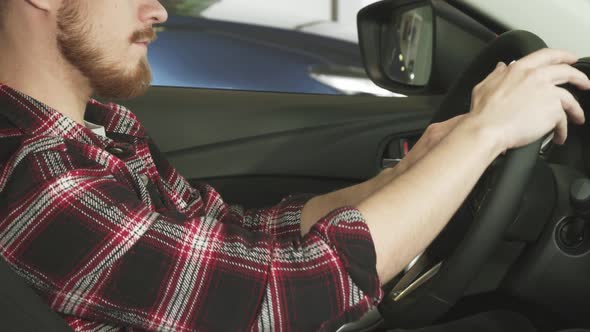 Cropped Shot of a Bearded Man Sitting in a Car Holding the Steering Wheel