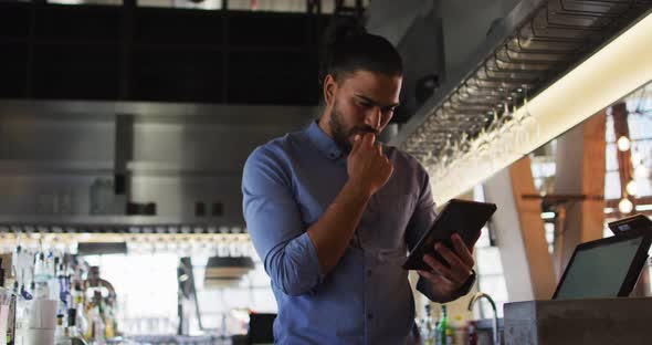 Portrait of mixed race male cafe owner using tablet and looking to camera alt
