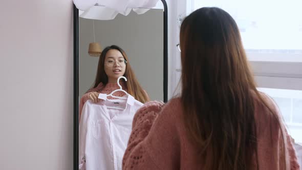 Middle Eastern Young Woman Chooses Clothes in Front of a Mirror in Bedroom at House alt