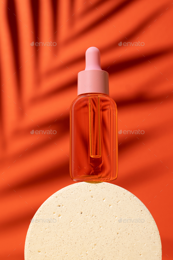 Cosmetic bottle with serum or oil on podium. Orange background with daylight and palm shadow. Sun