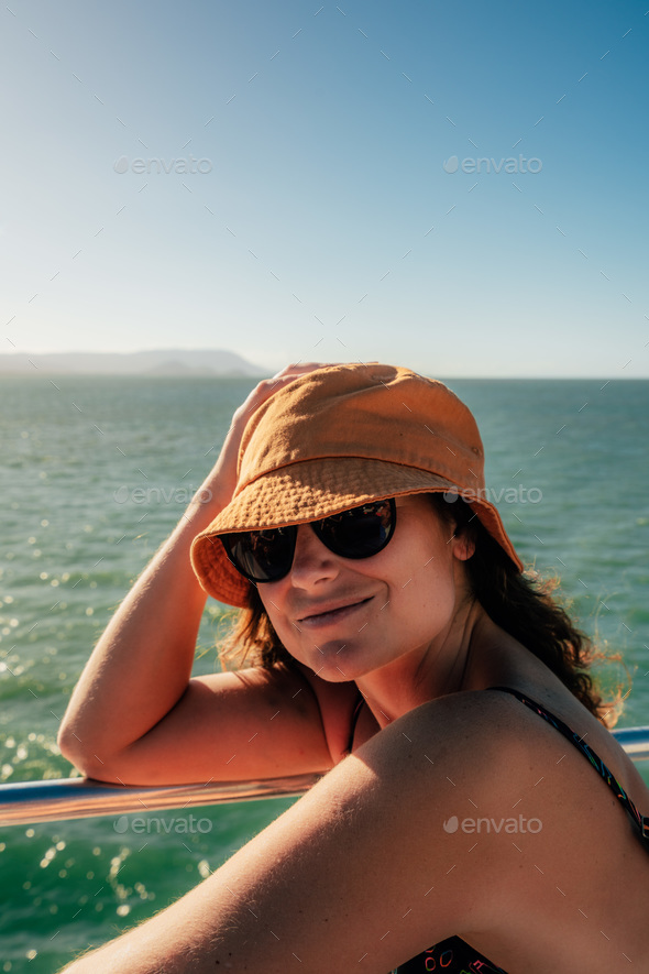 woman with hat and glasses enjoys the view of the great barrier reef on a boat