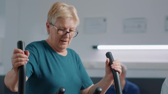 Elder Patient Doing Physical Exercise on Stationary Bicycle alt
