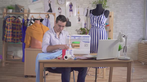 Man Fashion Designer Tailor Sews on a Sewing Machine alt