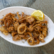 A plate of fried squid or calamari with lemon on a white plate - PhotoDune Item for Sale