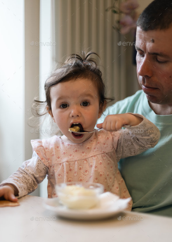 Portrait of a caucasian baby girl eating ice cream in a cafe.