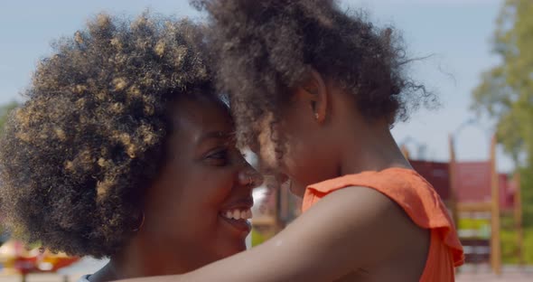 Close Up Portrait of Happy African Little Girl Hugging Mom Outdoors in Park alt