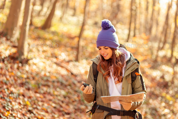 Woman reading a map and checking the compass while hiking Stock Photo ...