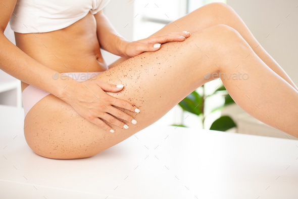 Closeup woman legs with coffee anti-cellulite wrapping scrub.