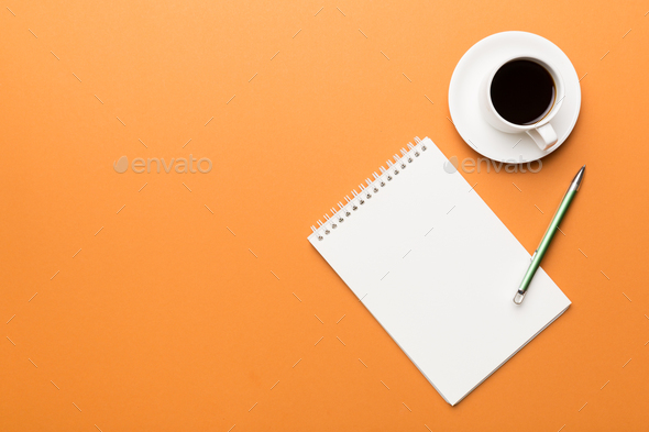 Top view of working table with blank paper notebook, cup of coffee
