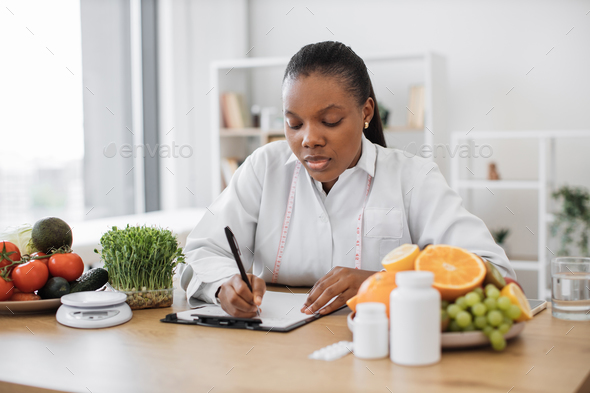 Specialist writing down client\'s diet data at office desk