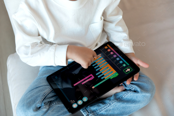 A preschool kid programmer coding at tablet pc, uses machine language