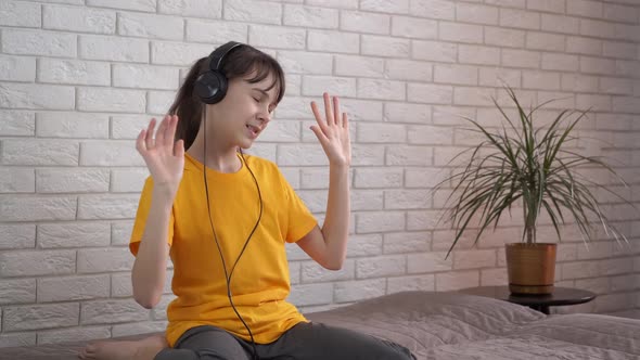 Child in happy dance in headphones. alt