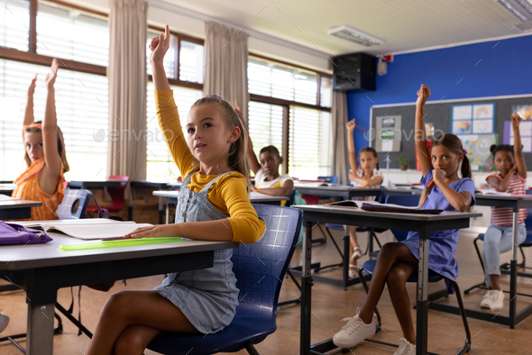 elementary students raising hands in class