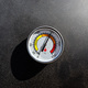A round thermometer showing 150 degrees Celsius placed on a charcoal grill. - PhotoDune Item for Sale