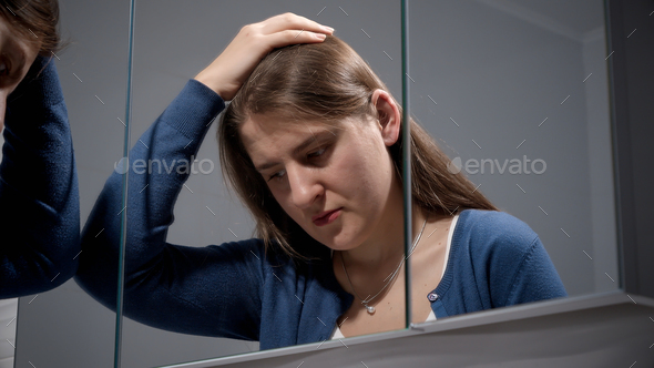 Portrait of angry woman trying to calm down looking in mirror. Concept of depression, stress
