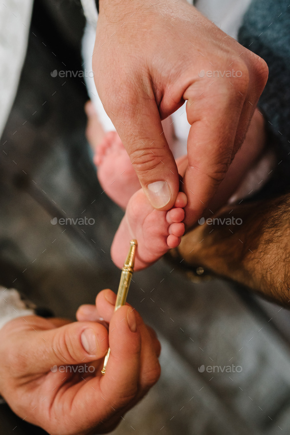 Baptism ceremony of a baby. Close up of tiny baby feet, the sacrament of baptism. The godfather