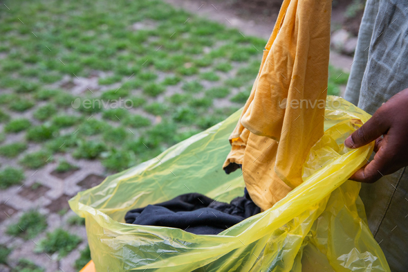 A woman throws used clothes into a recycling bag, waste sorting in order not to pollute