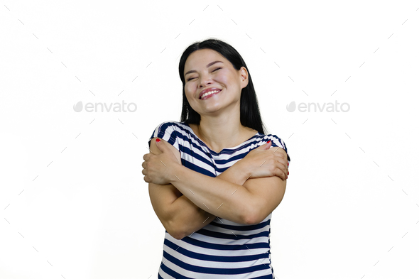 Happy young beautiful asian woman hugging herself isolated on white.
