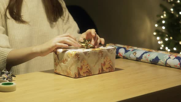 Female Decorates Gift with Bow