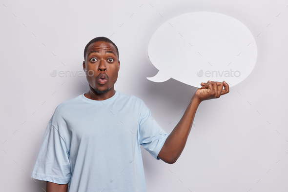 Black man with expression of shock holds blank speech bubble for your promotional content cannot