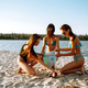 Three young girls pick up trash on the beach. Environmental pollution.  Ecological problem. Stock Photo by maxbelchenko
