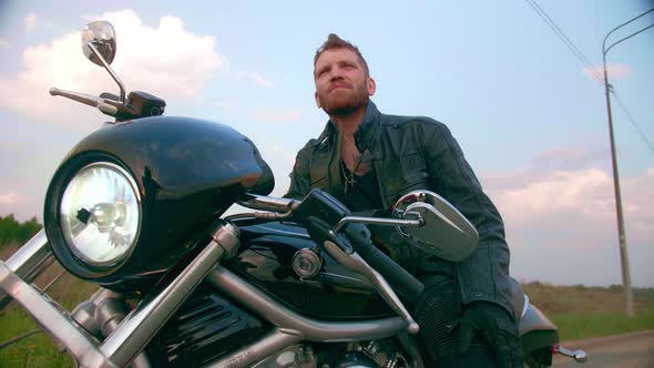 Young Man Sitting on Motorcycle on the Road at Sunset Slow Motion