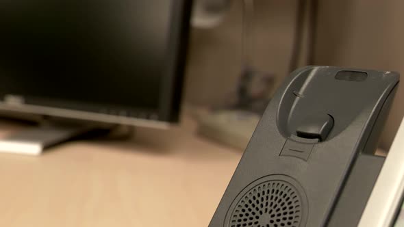 A close up of a hand picking up and slamming an office phone down a couple of times onto the phone b alt