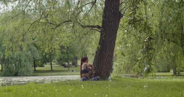 Shaped Middleaged Woman Stretching Her Arm Isolated Against the Background of a Tree and Lake alt