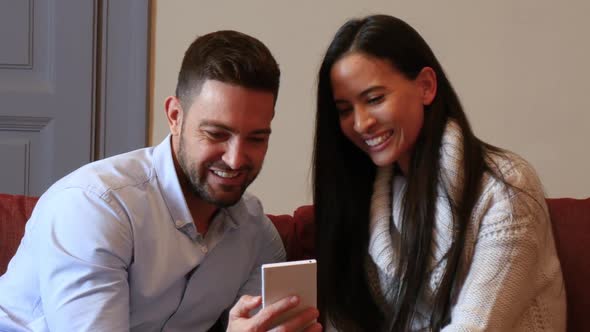 A young couple discussing content on a smartphone