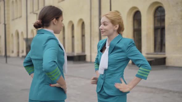 Two Annoyed Young Stewardesses Arguing Outdoors on City Street. Portrait of Irritated Elegant Slim alt