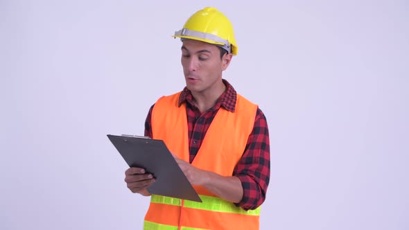 Young Happy Hispanic Man Construction Worker Talking While Reading on Clipboard