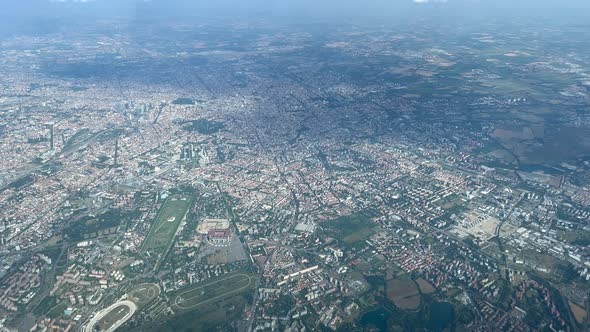 Left side aerial view of the city of Milan (Milano), Italy, during initial climb, daylight alt