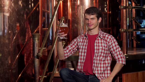 Young Male Brewer Examining Freshly Brewed Beer, Working at His Brewery alt