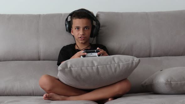 Boy Playing Video Games On The Console The On The Sofa At Home