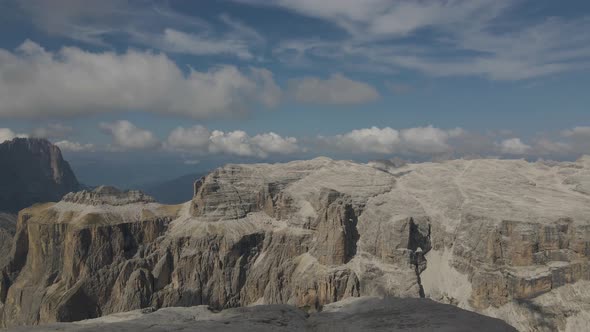 Aerial view: Dolomites in Val Gardena, Italy. High mountain peak with cloudy sky during a sunny day. alt