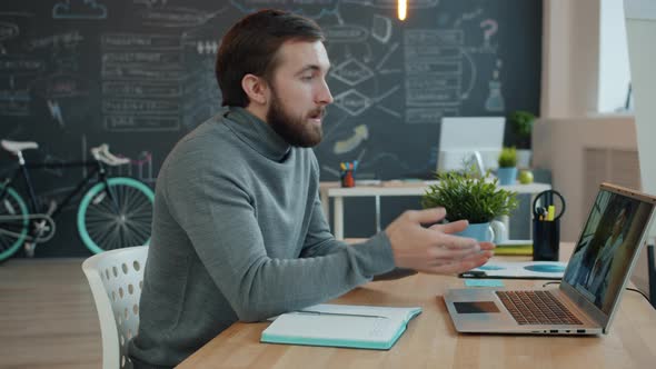 Young Man Making Internet Call Talking To Friends Online From Open Space Office alt