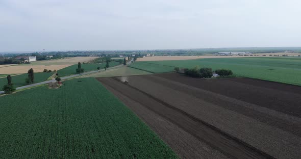 Tractor Tilling Soil Surrounded By Corn And Wheat Crops In The Field alt