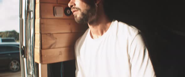 Young man sitting inside van waiting for something alt