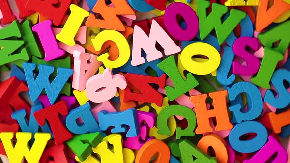 Multi-colored letters are scattered in a chaotic manner moving in a circular rotation. alt