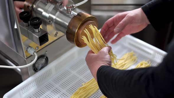 Man working inside pasta factory doing fresh made spaghetti with machine