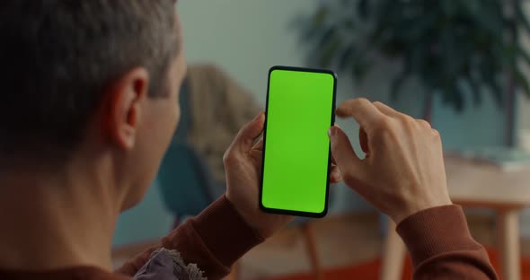 Caucasian Man Scrolling on Green Screen of Smartphone alt