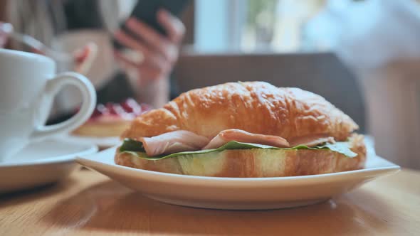 Croissant and Meat on a Girl's Table at Lunchtime alt