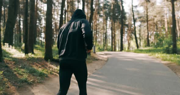 Slow Motion Shot of Man Running Through Pine Forest on Path in Woods. Runner Training Fitness and alt