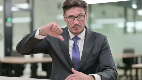 Disappointed Middle Aged Businessman Doing Thumbs Down  alt