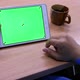 Man is using tablet with green screen on the wooden table - VideoHive Item for Sale