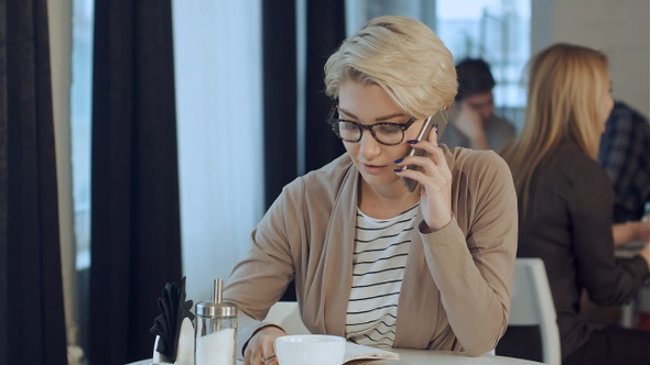 Happy businesswoman talking on the phone in a coffee shop