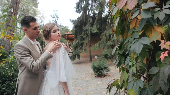Close-up View of Happy European Wedding Couple in Nature. Groom in Suit Hugs the Bride and alt
