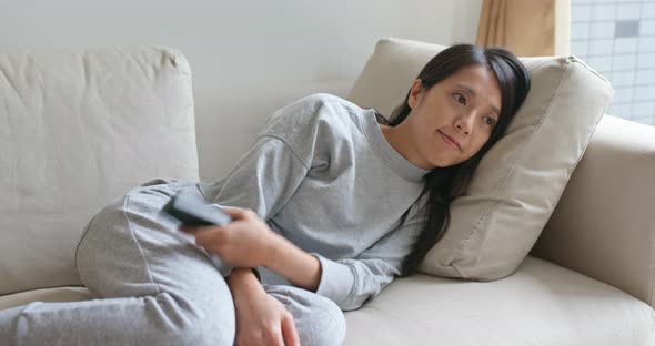 Woman watch tv and lying on sofa at home alt
