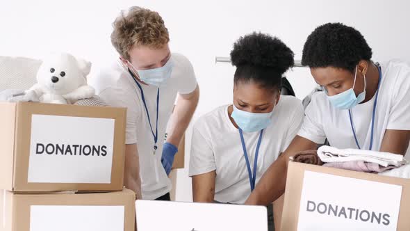 Volunteers Wearing Masks Sorting Clothes Donations During Pandemic alt