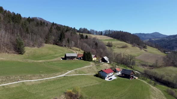 Rustic houses on the hills surround by forest and mountains. Aerial view alt